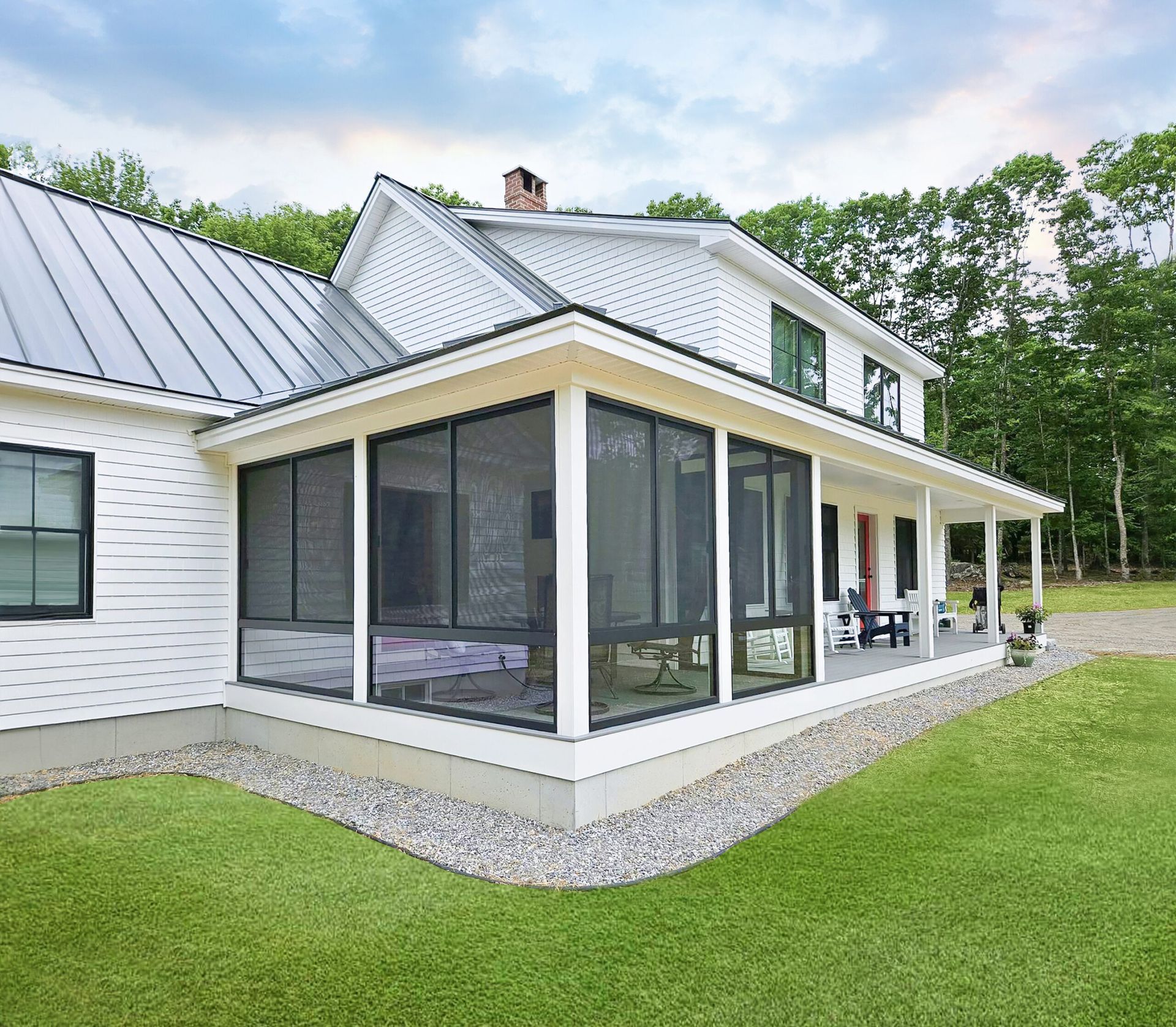 White house with screened porch, green lawn, and gravel border.