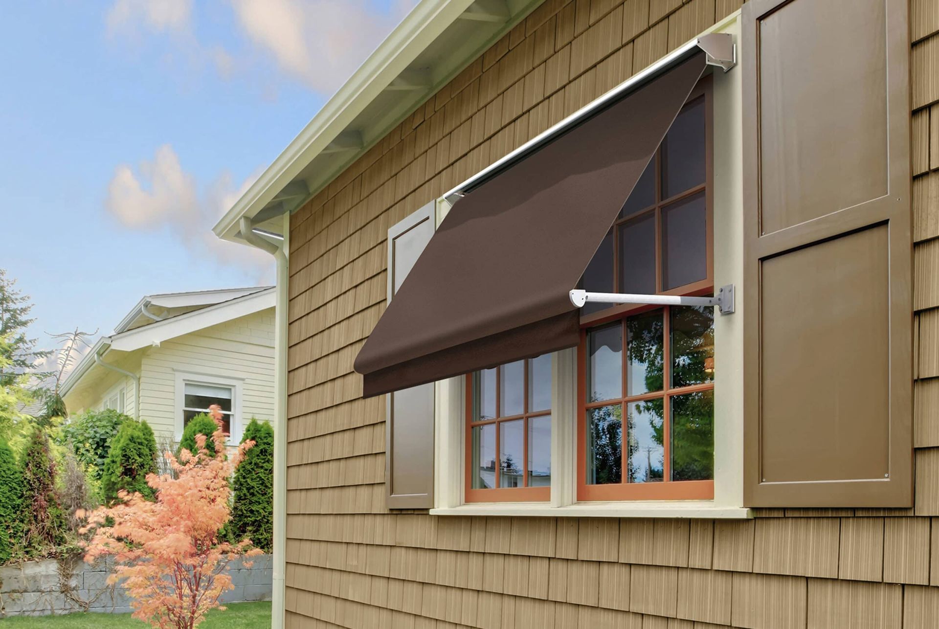 Brown awning over a window with brown shutters on a brown shingled house.