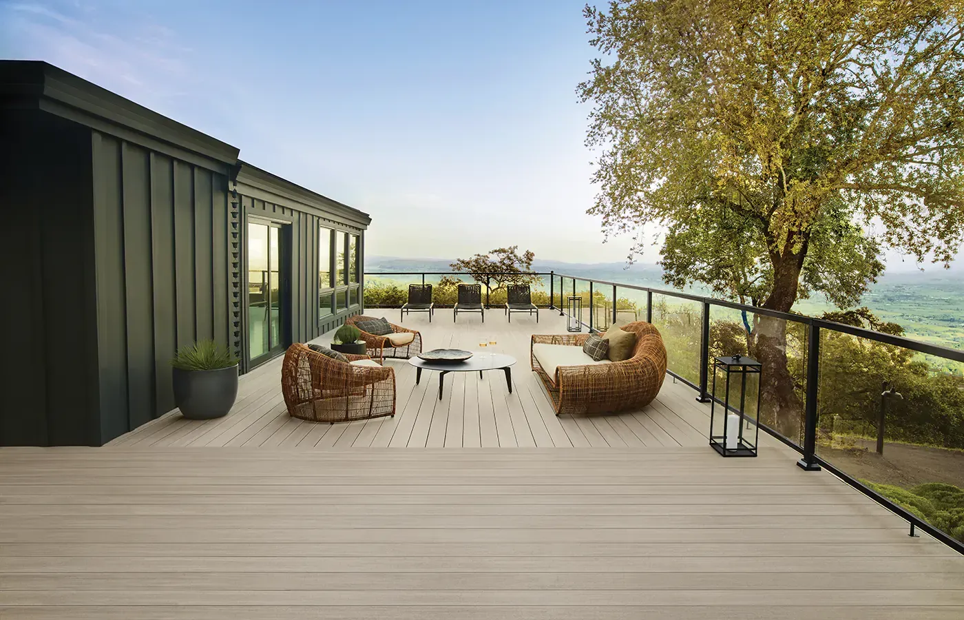 Outdoor deck with seating overlooking a scenic valley, next to a dark house.