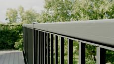 Black metal railing with a gray top rail; trees in background.