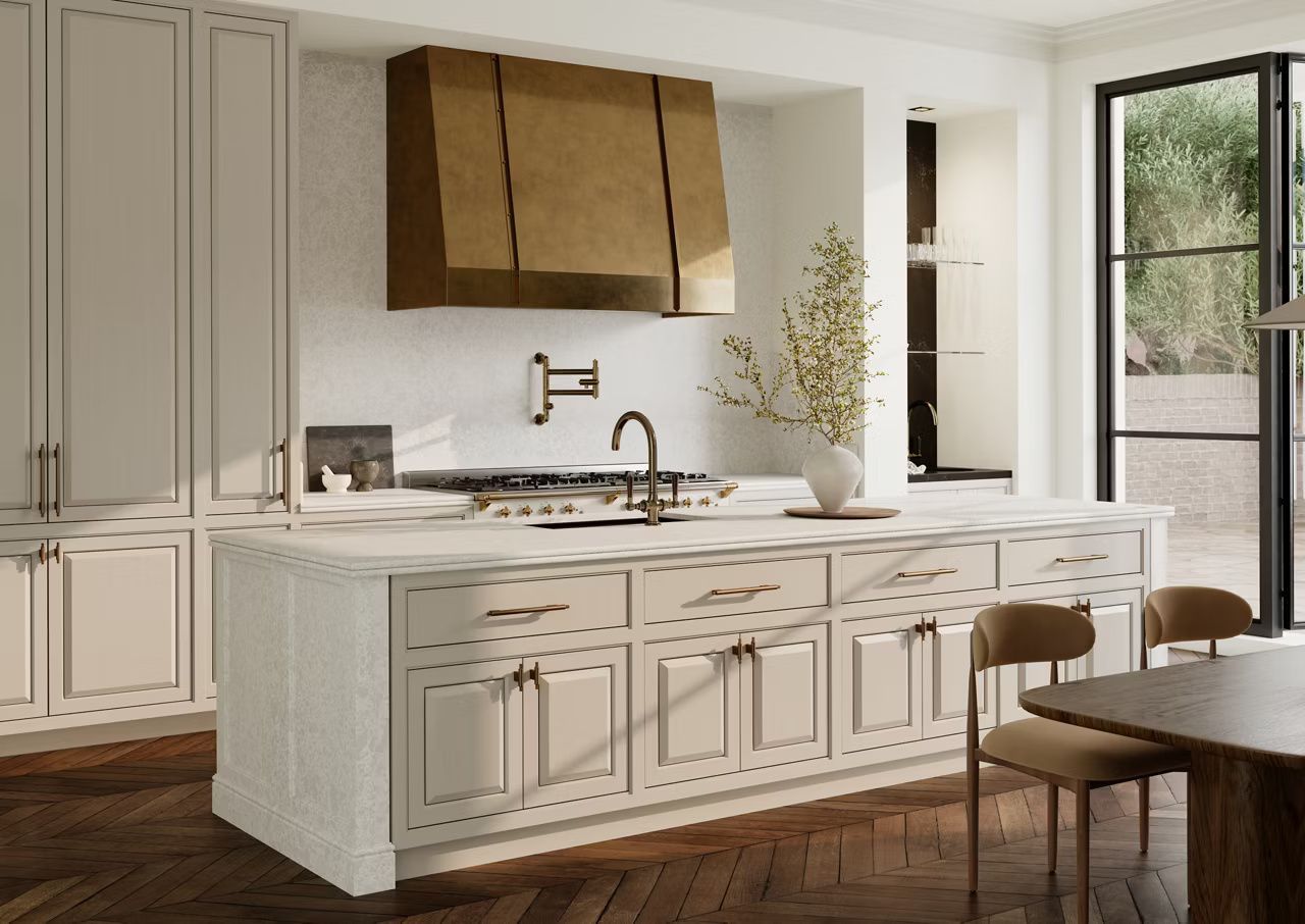 Elegant kitchen with a gold range hood, white cabinets, and a large island.