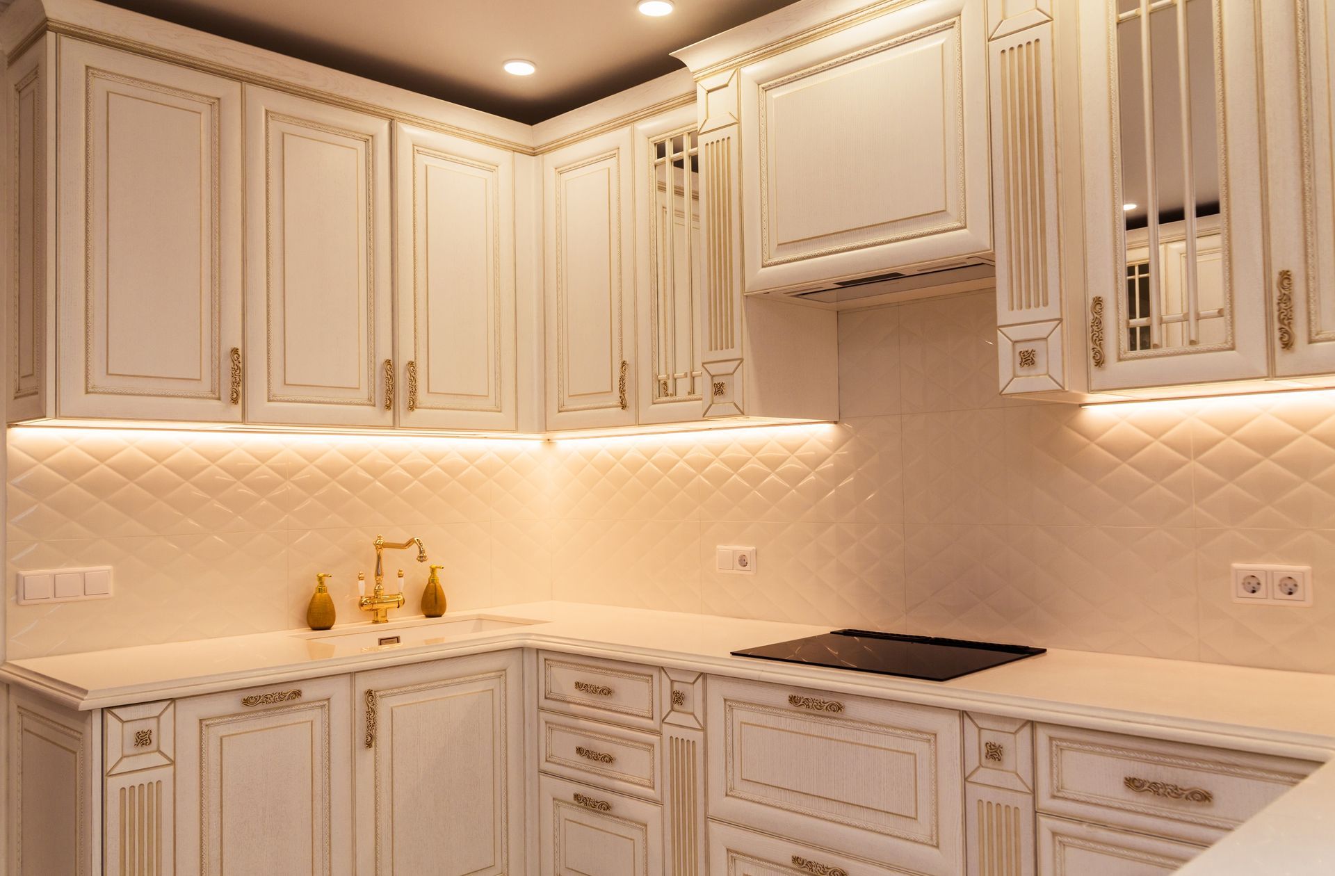 Cream-colored kitchen cabinets with gold trim and under-cabinet lighting.