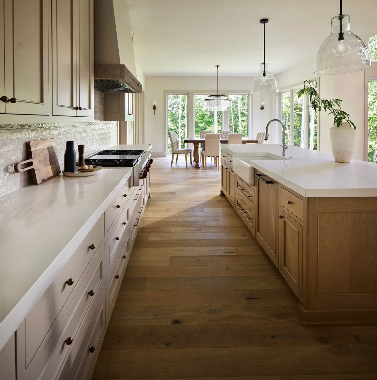 Spacious kitchen with light wood cabinets, white countertops, and a view of a dining area with windows.