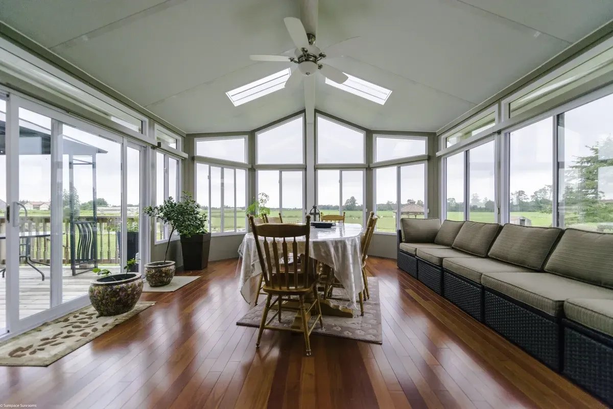 Sunroom with wooden floors, large windows, a dining table, and a built-in couch.
