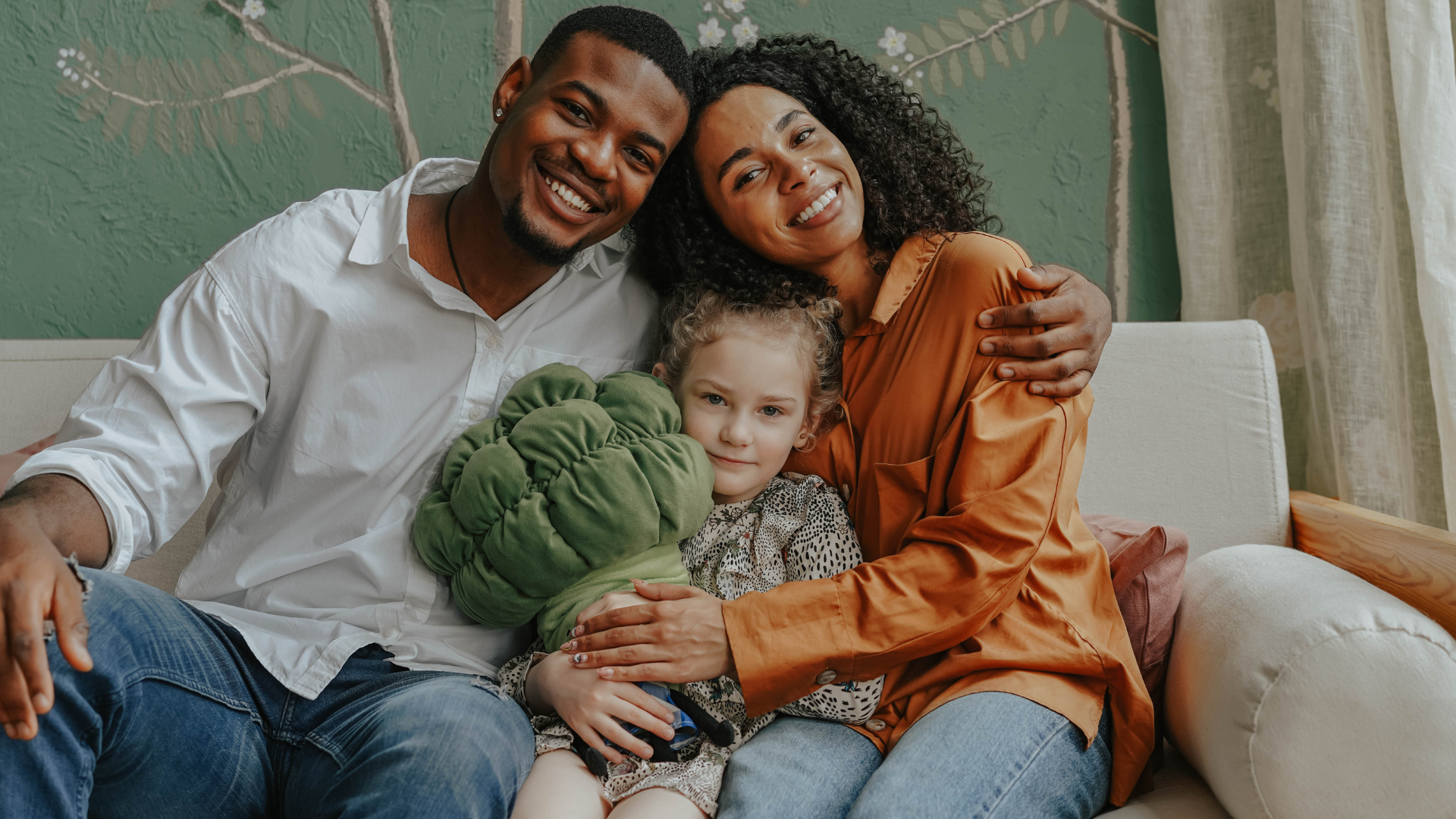 A family is sitting on a couch hugging each other and smiling.