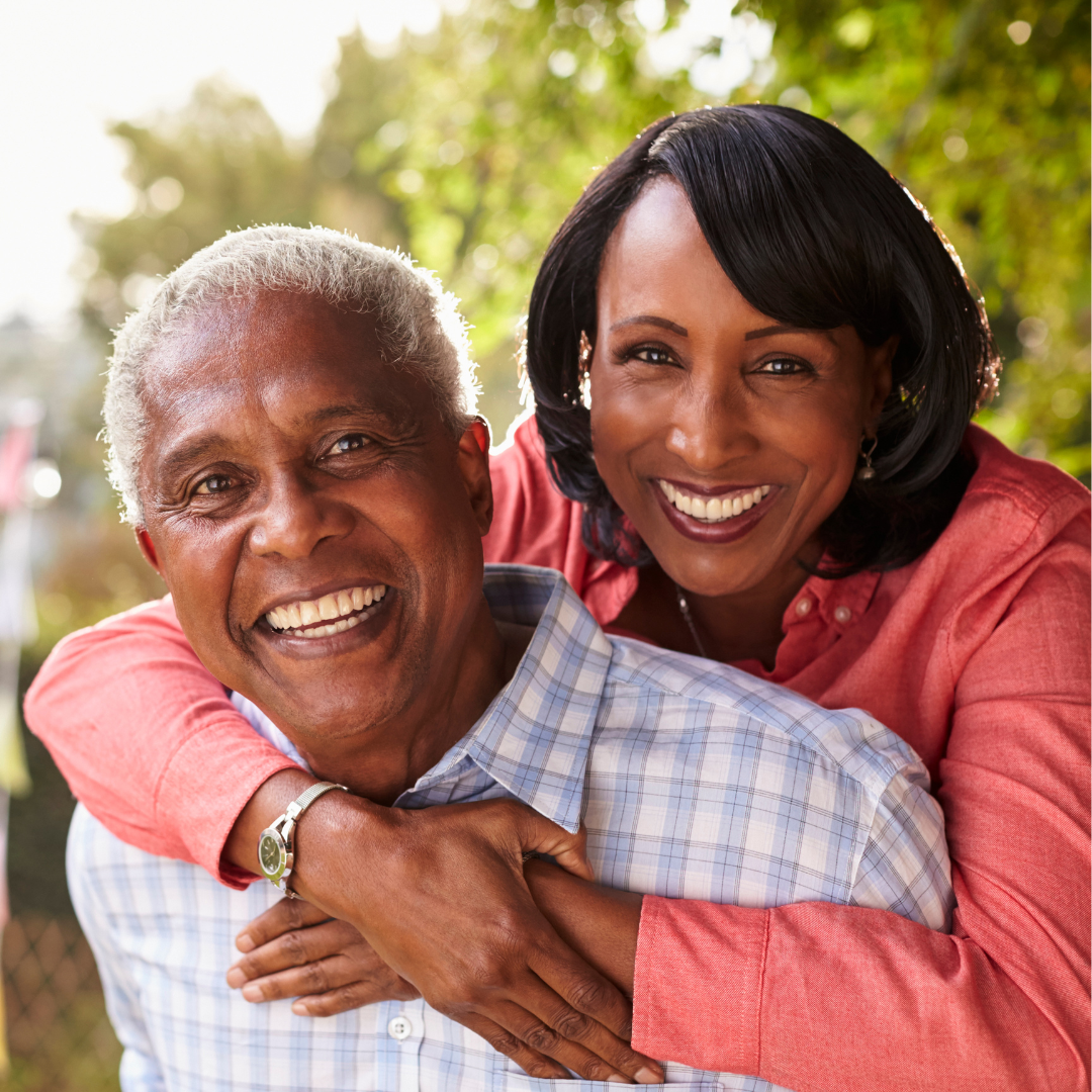 A woman is giving a man a piggyback ride and they are smiling for the camera