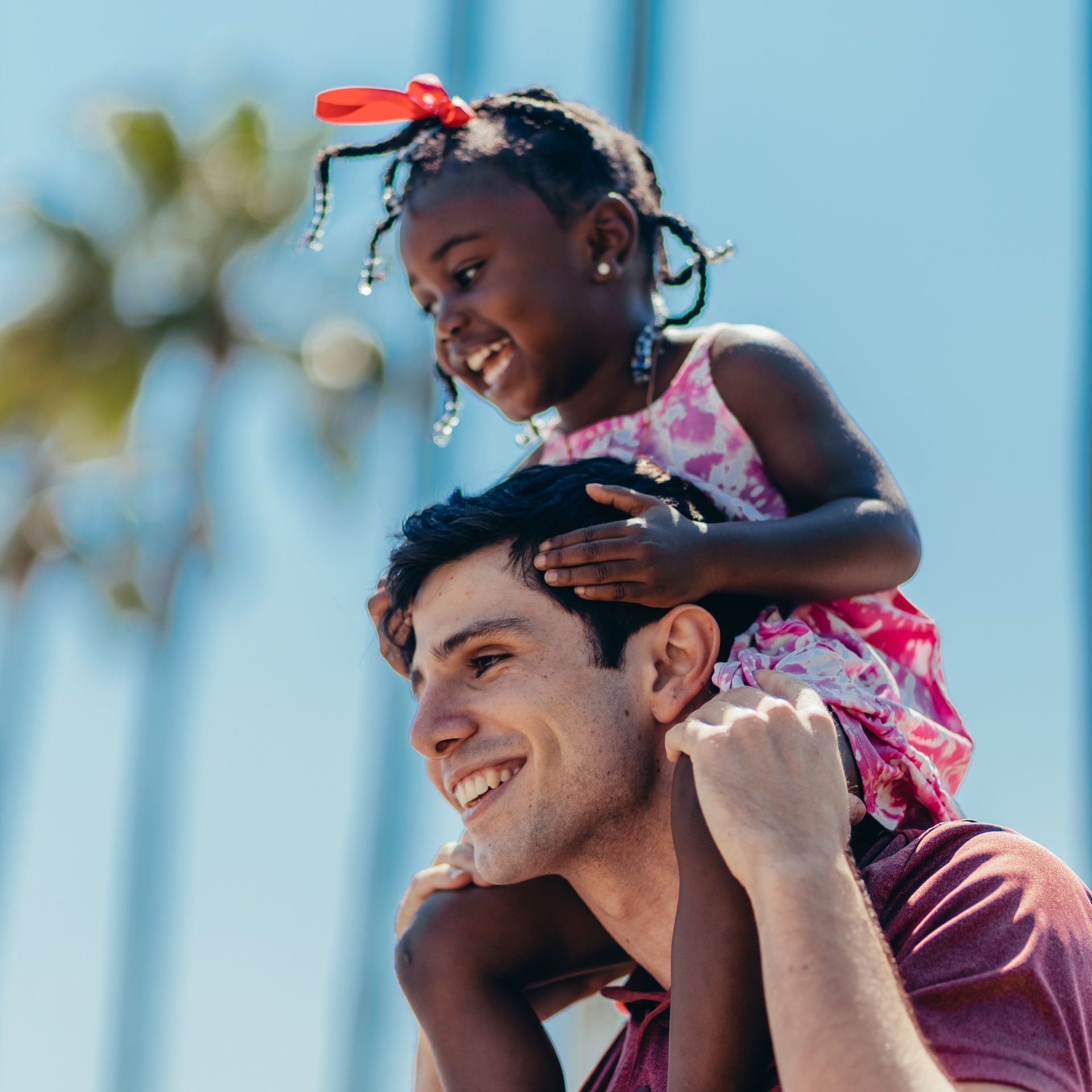 A little girl is sitting on a man 's shoulders