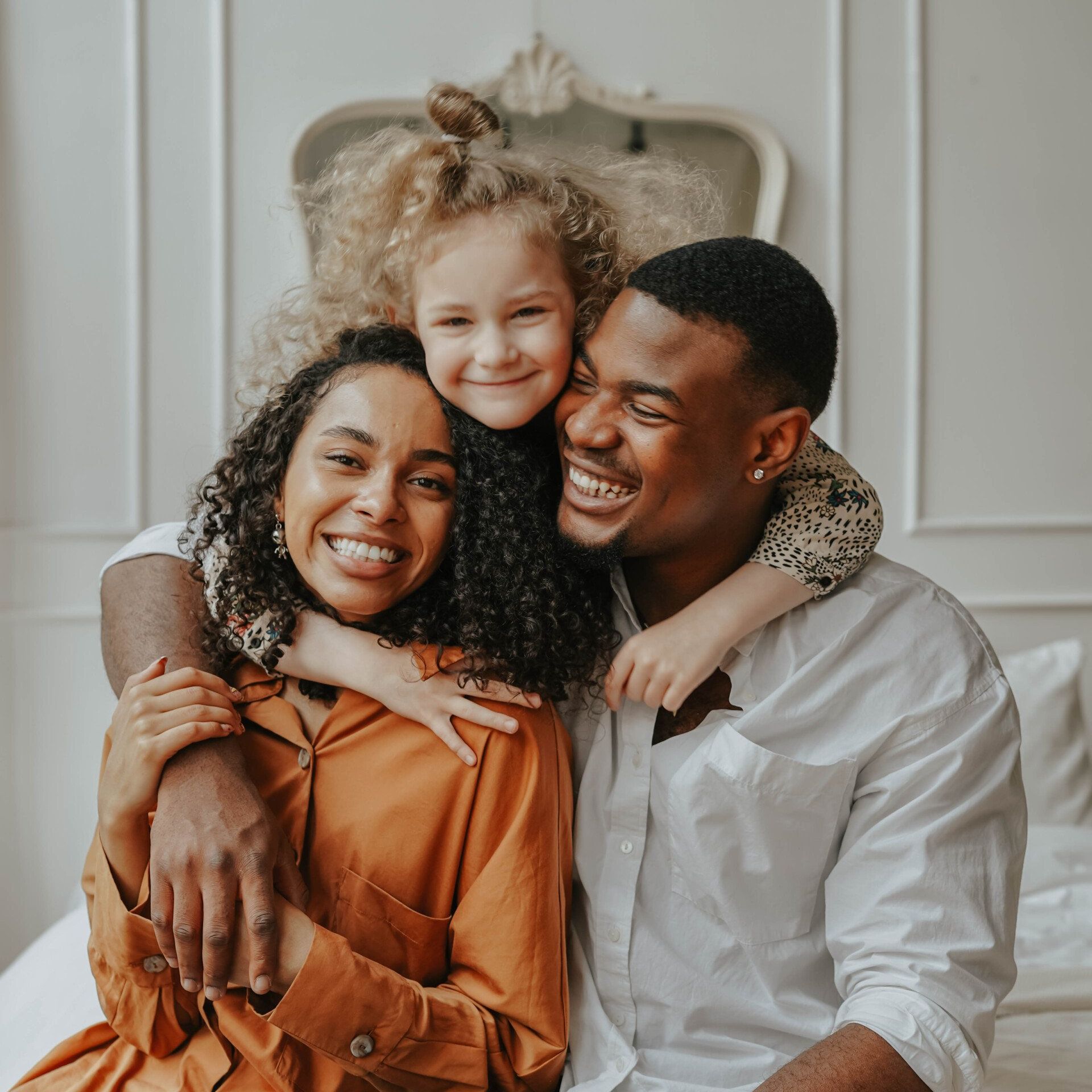 A man , woman and child are posing for a picture while sitting on a bed.