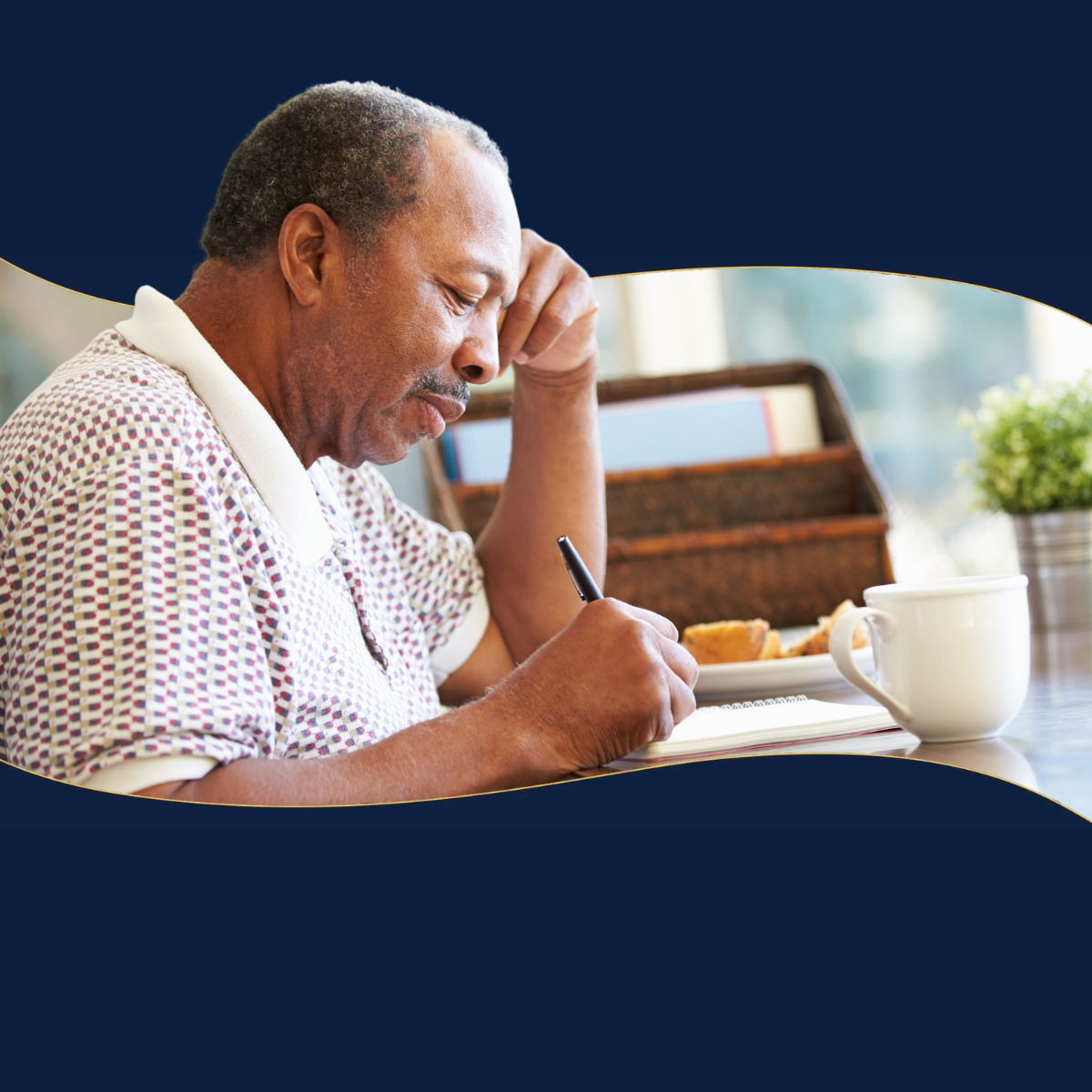 A man is sitting at a table writing in a notebook