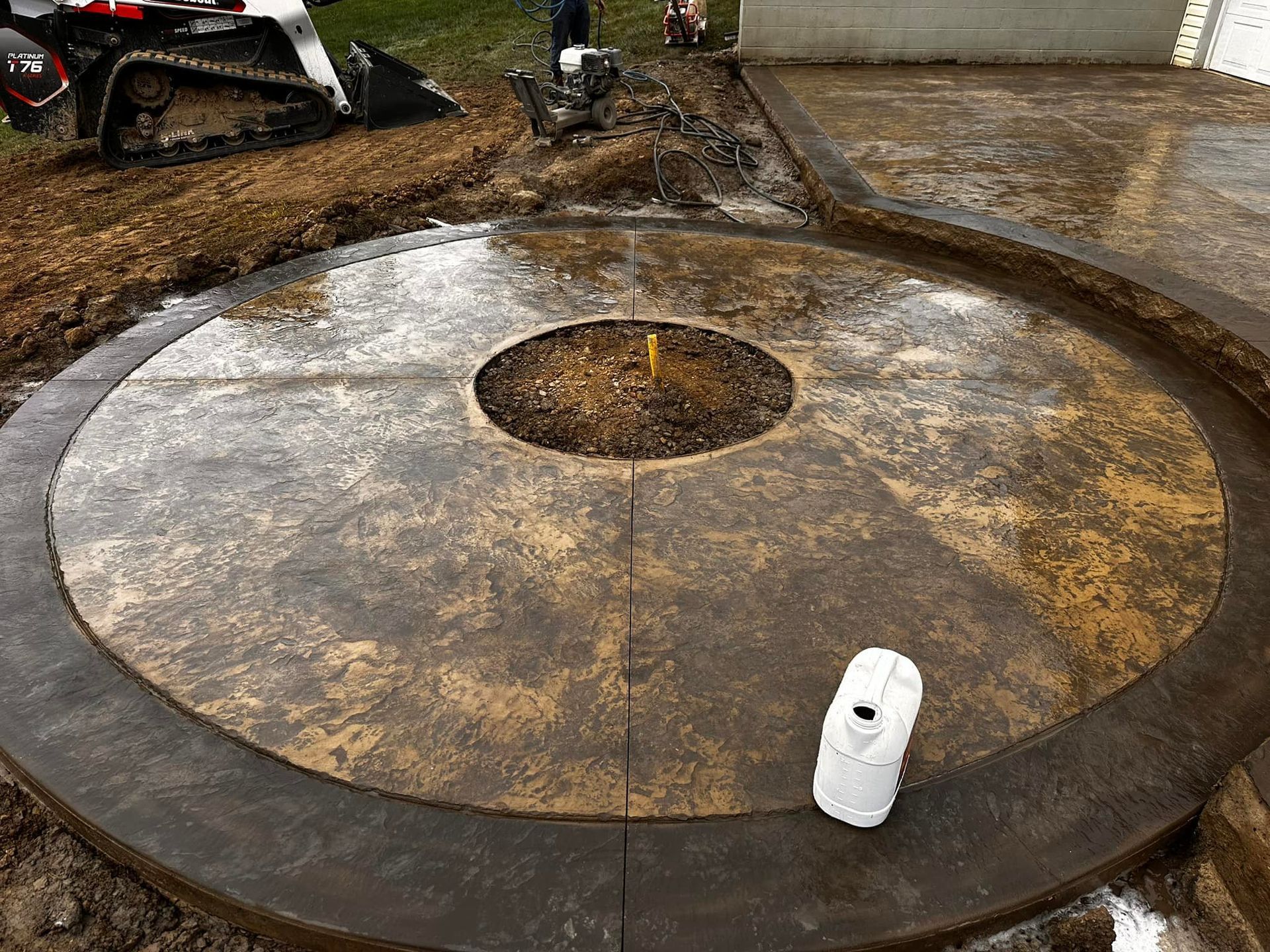 A circular concrete patio with a fire pit in the middle.
