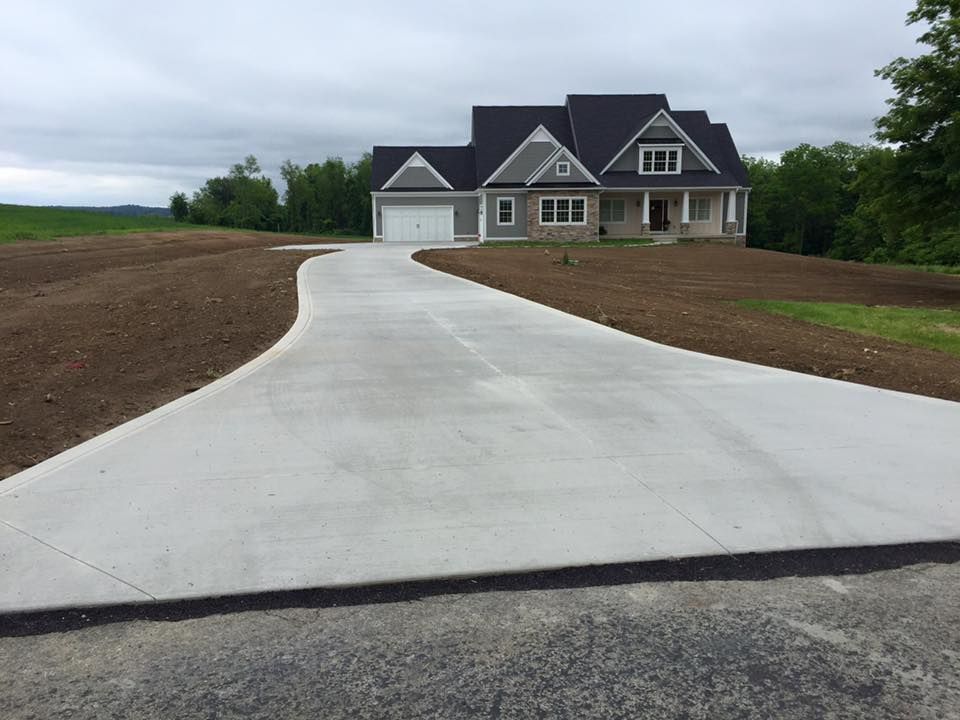 A concrete driveway leading to a large house