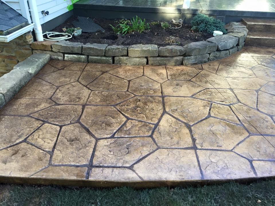 A concrete walkway with a brick wall and a planter in the background.