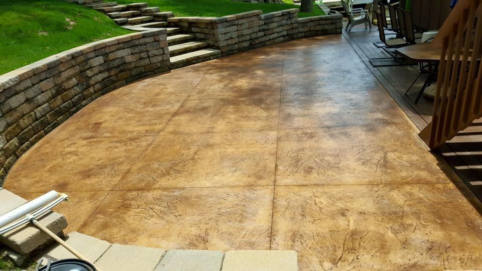 A concrete patio with a brick wall and stairs in the background.