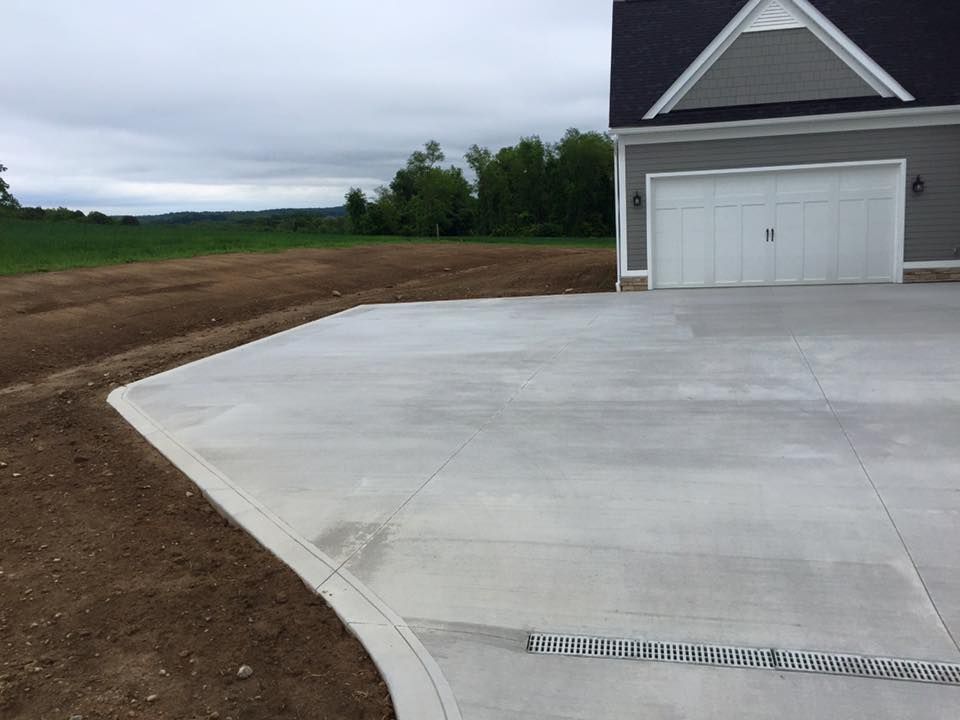 A concrete driveway leading to a house with a white garage door.