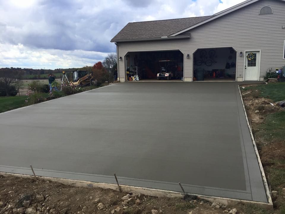A concrete driveway is being built in front of a house.