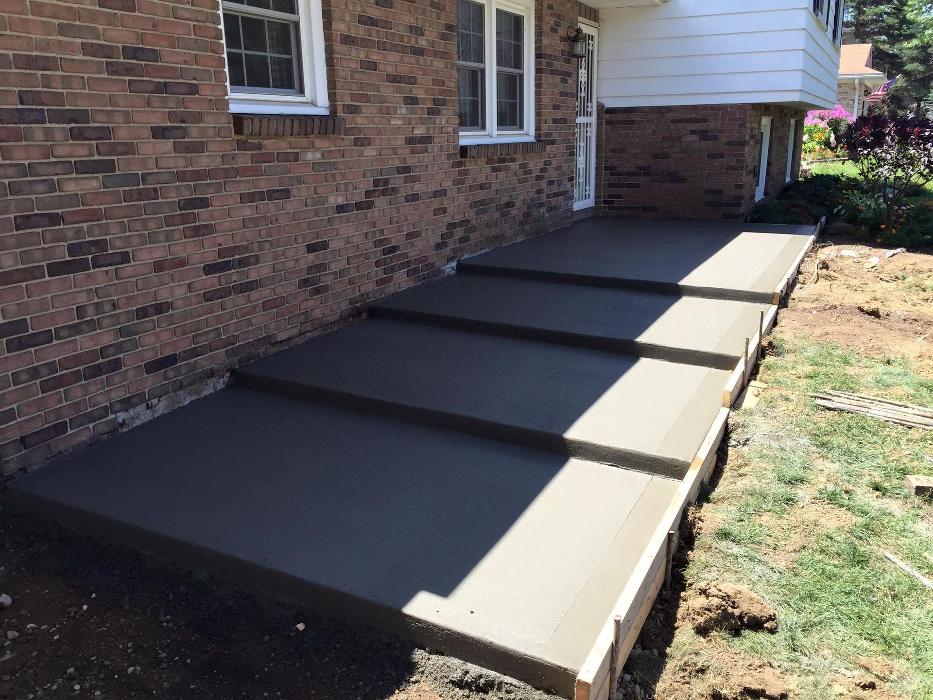 A brick house with a concrete walkway in front of it