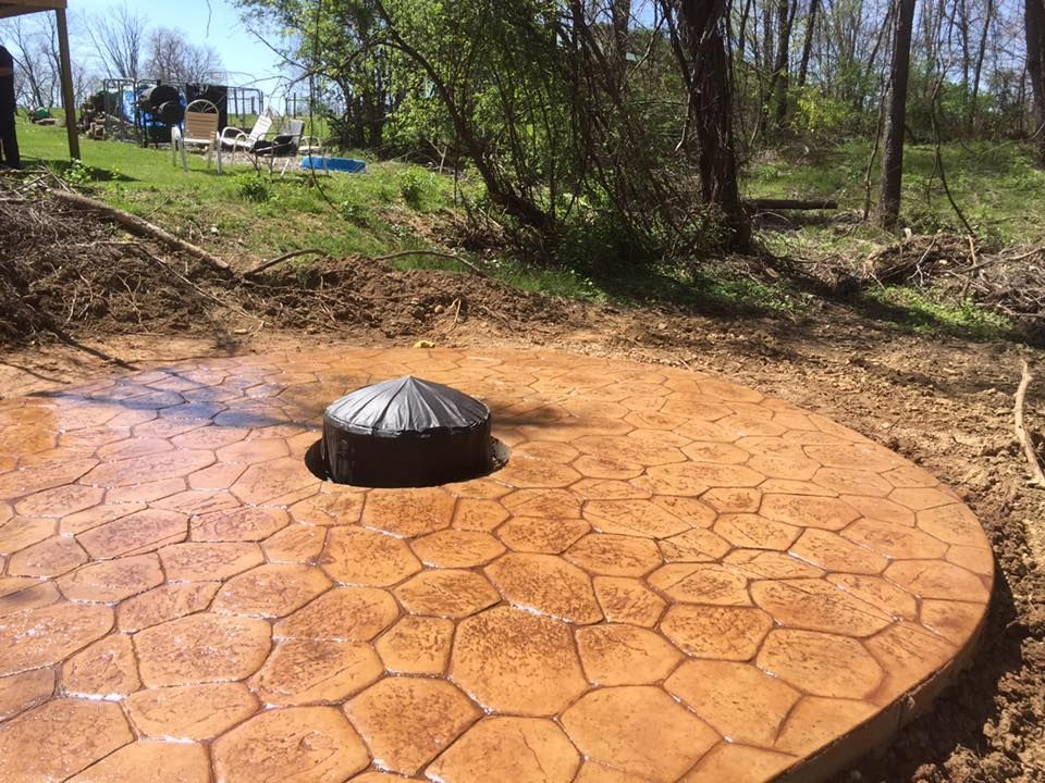A concrete patio with a fire pit in the middle of it.