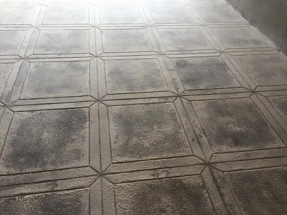 A close up of a concrete floor with square tiles on it.
