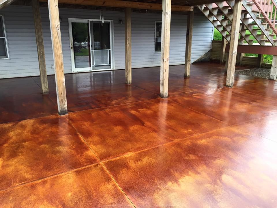 A stained concrete patio with stairs leading up to a house.