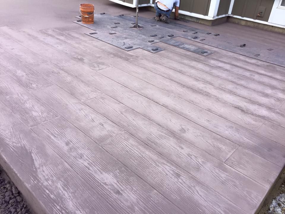 A man is sitting on a wooden deck next to a house.