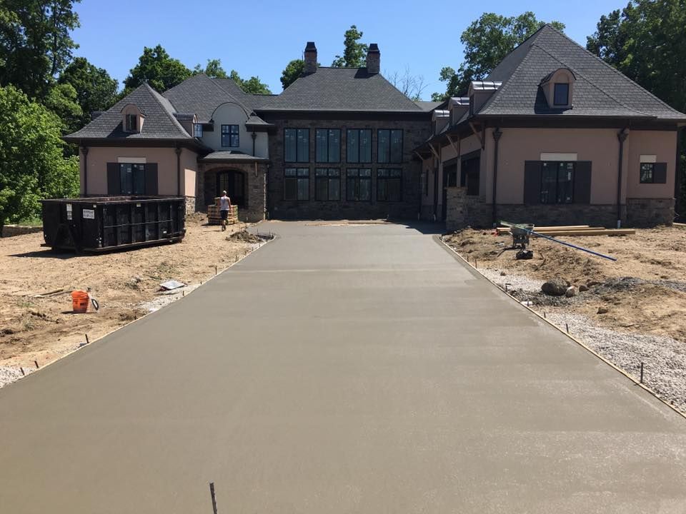 A concrete driveway is being built in front of a large house.