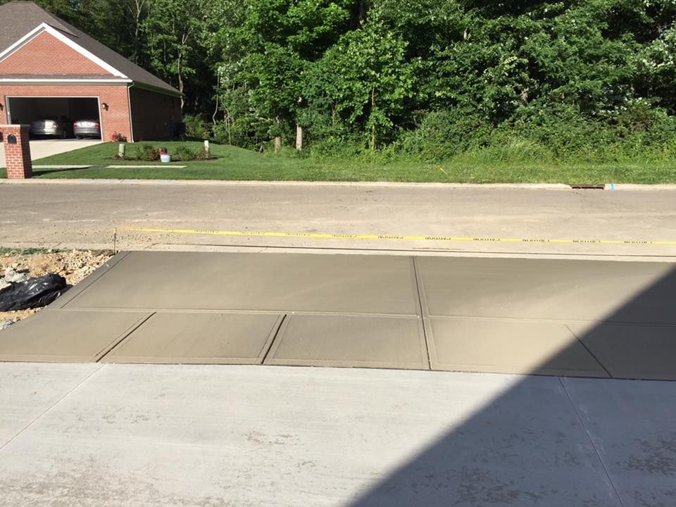 A concrete driveway with a brick house in the background
