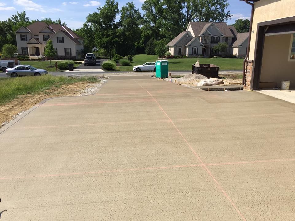 A concrete driveway with houses in the background