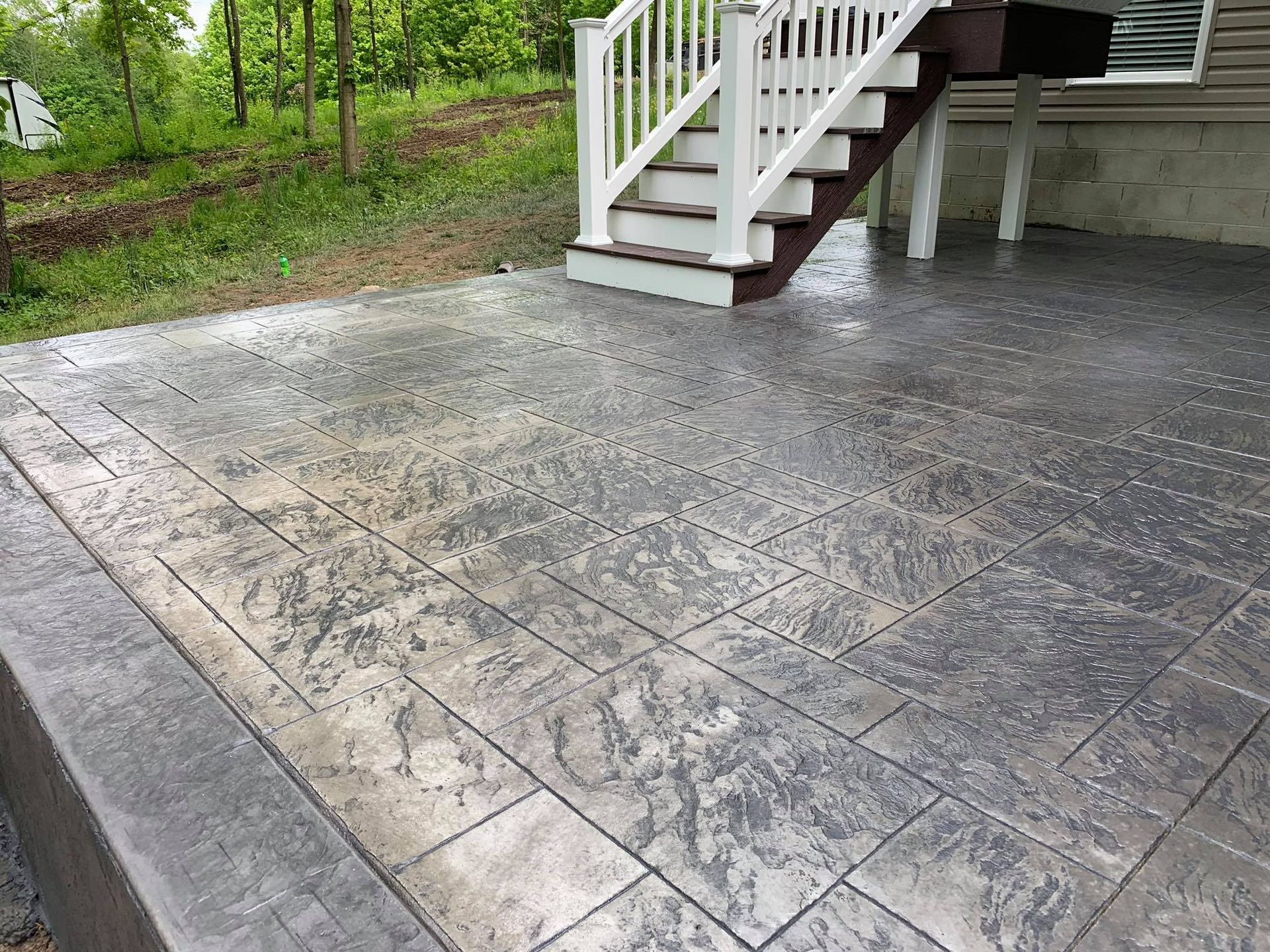 A concrete patio with stairs leading up to a deck.