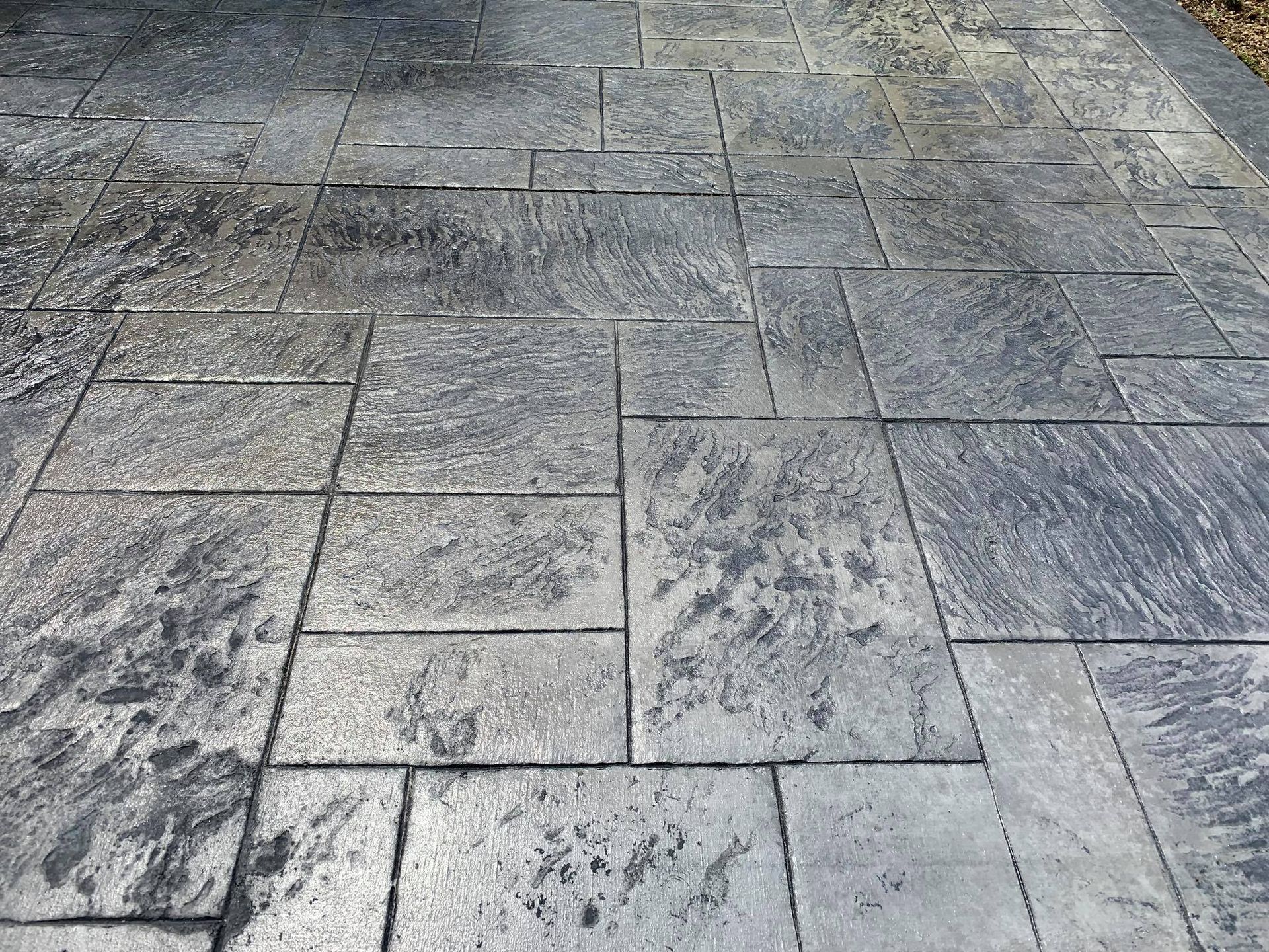 A close up of a concrete driveway with a gray tile pattern.