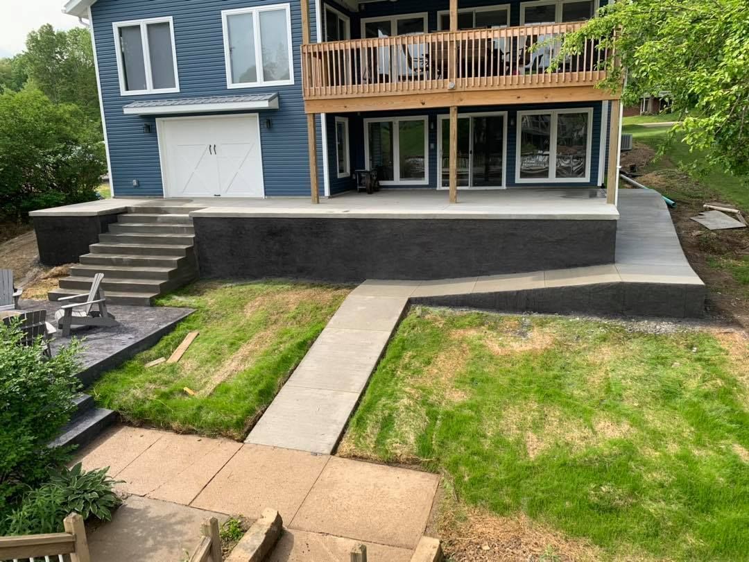 A large blue house with a large deck and stairs leading to it.