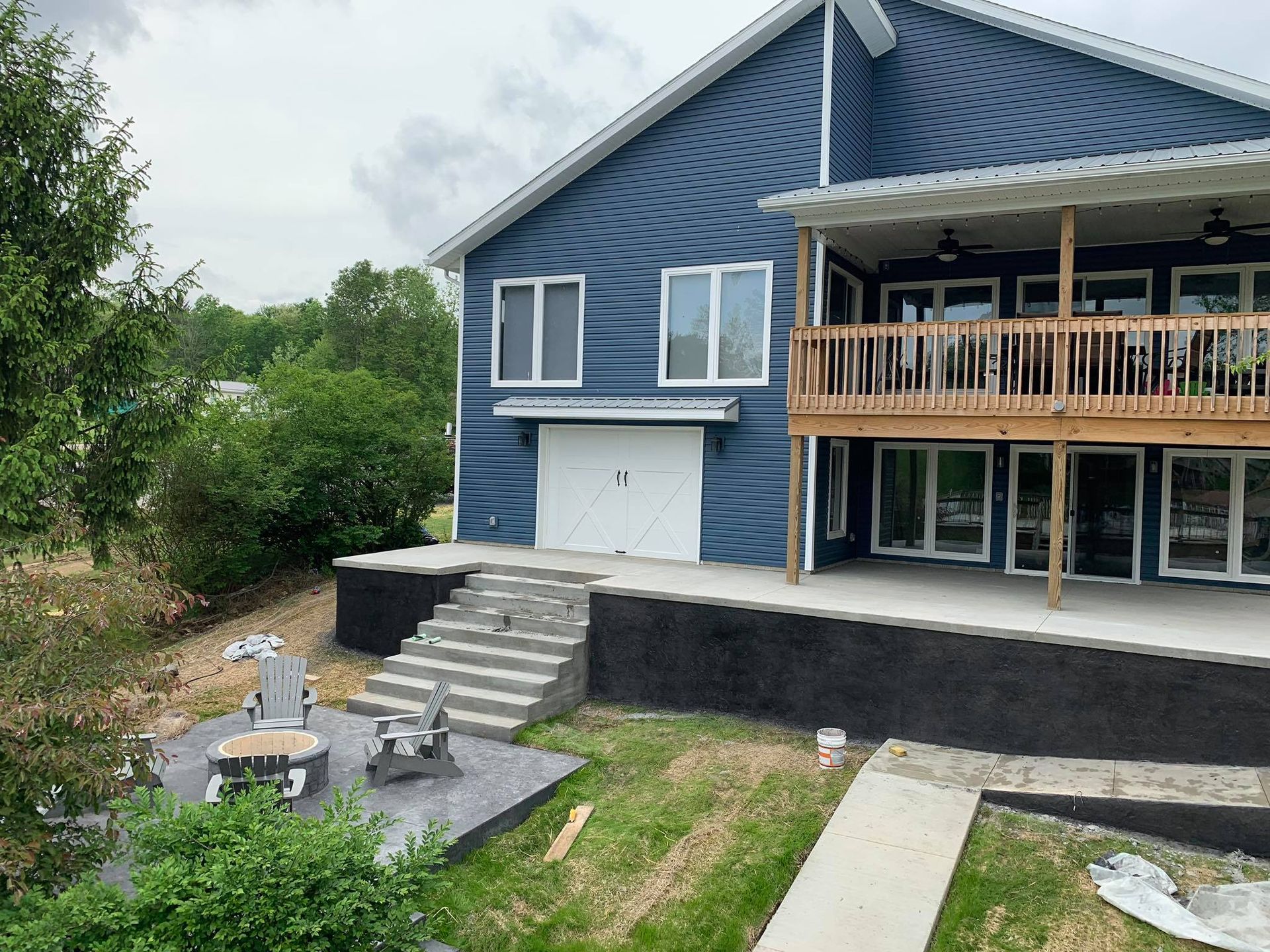 A large blue house with a large deck and stairs leading up to it.