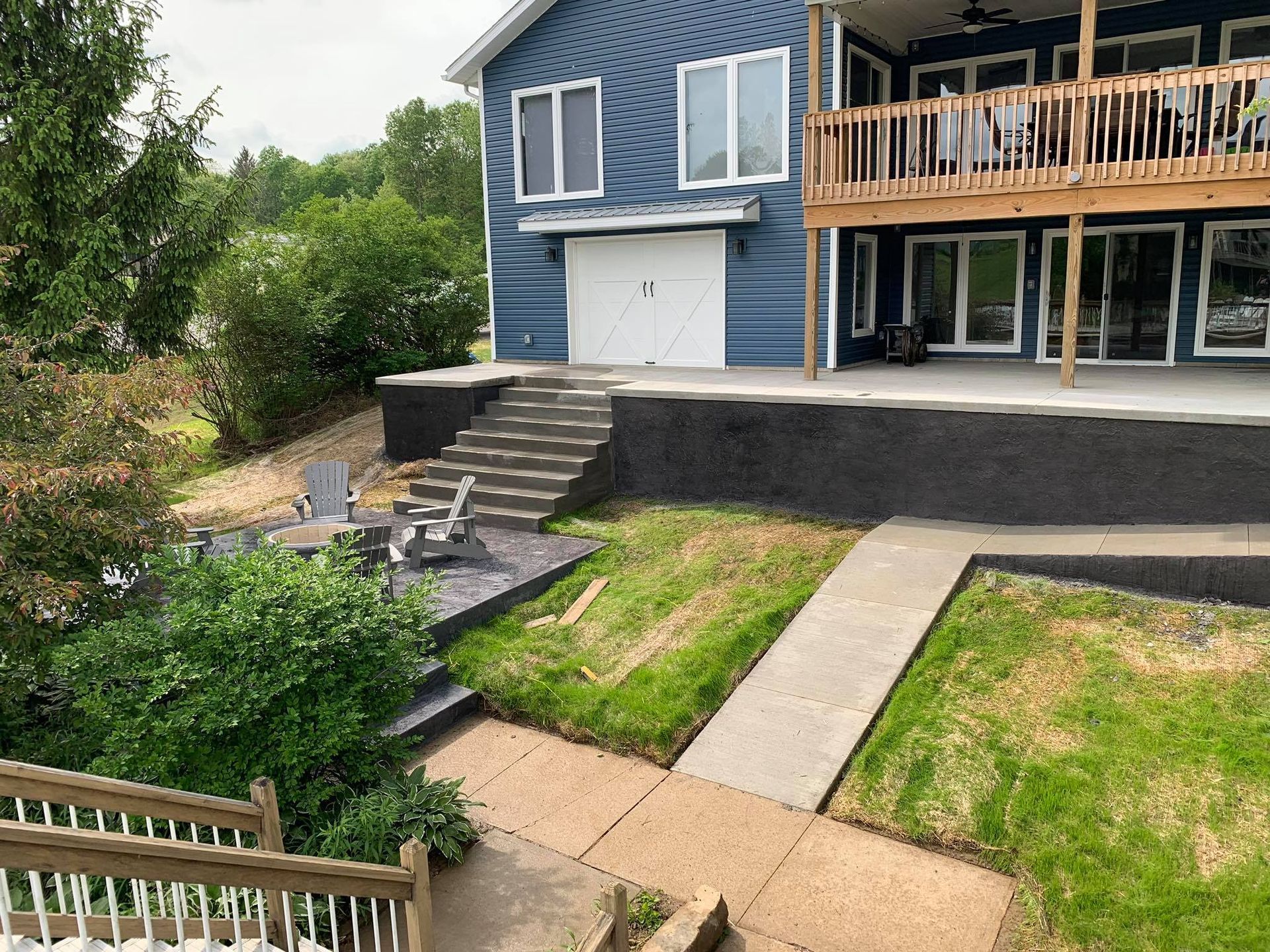 A large blue house with a large deck and stairs leading up to it.
