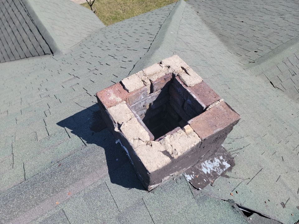 A brick chimney on top of a green roof