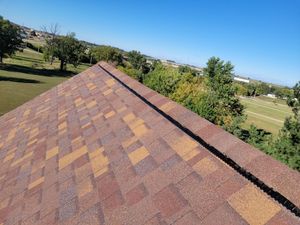 A roof with a lot of shingles and trees in the background