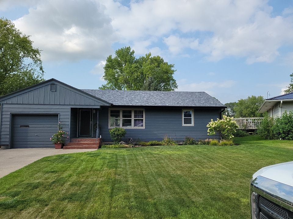A blue house with a garage and a truck parked in front of it.