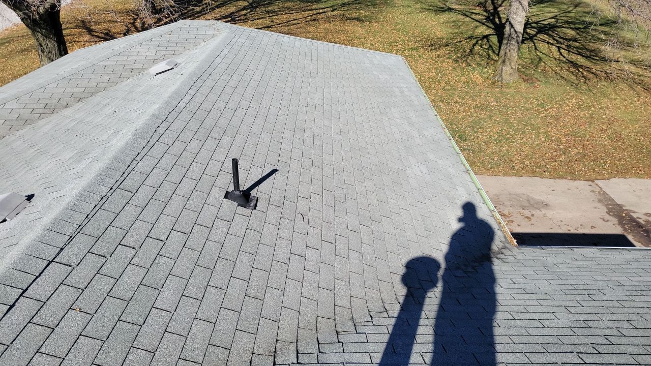 A shadow of a person is cast on the roof of a house.