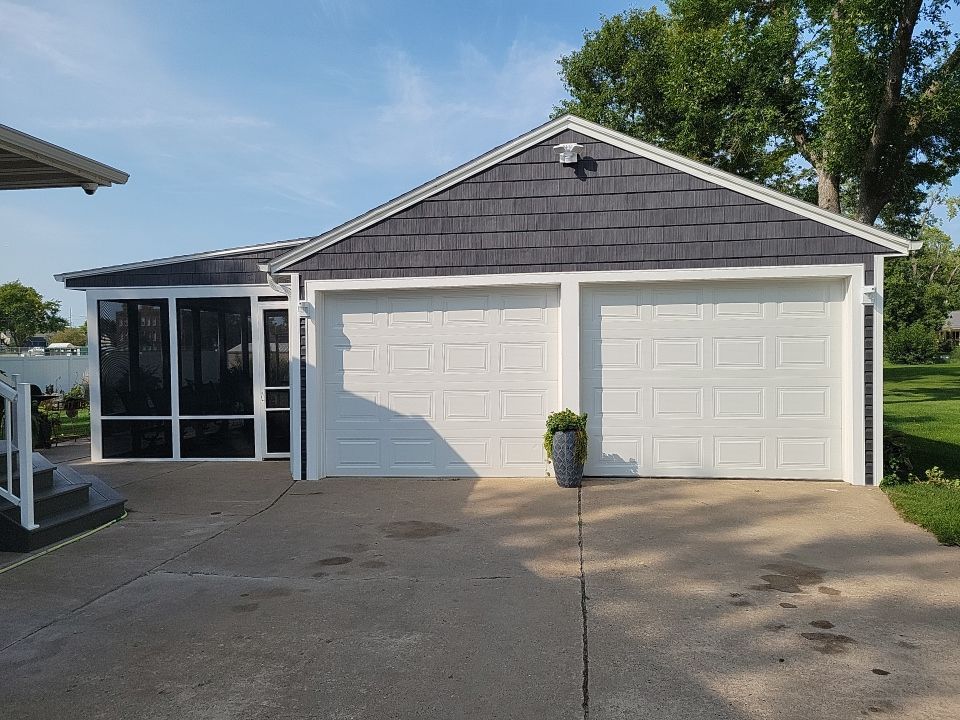 A house with two garage doors and a screened in porch.