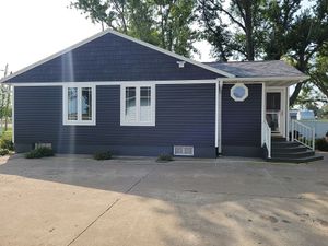 A blue house with white trim and windows is for sale.