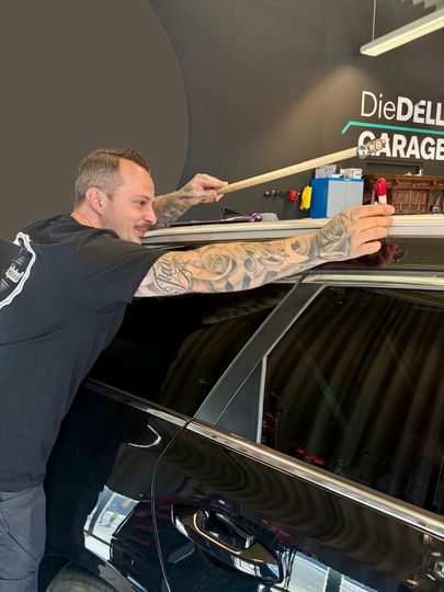 Ein Mann arbeitet in einer Garage an einem Autodach.