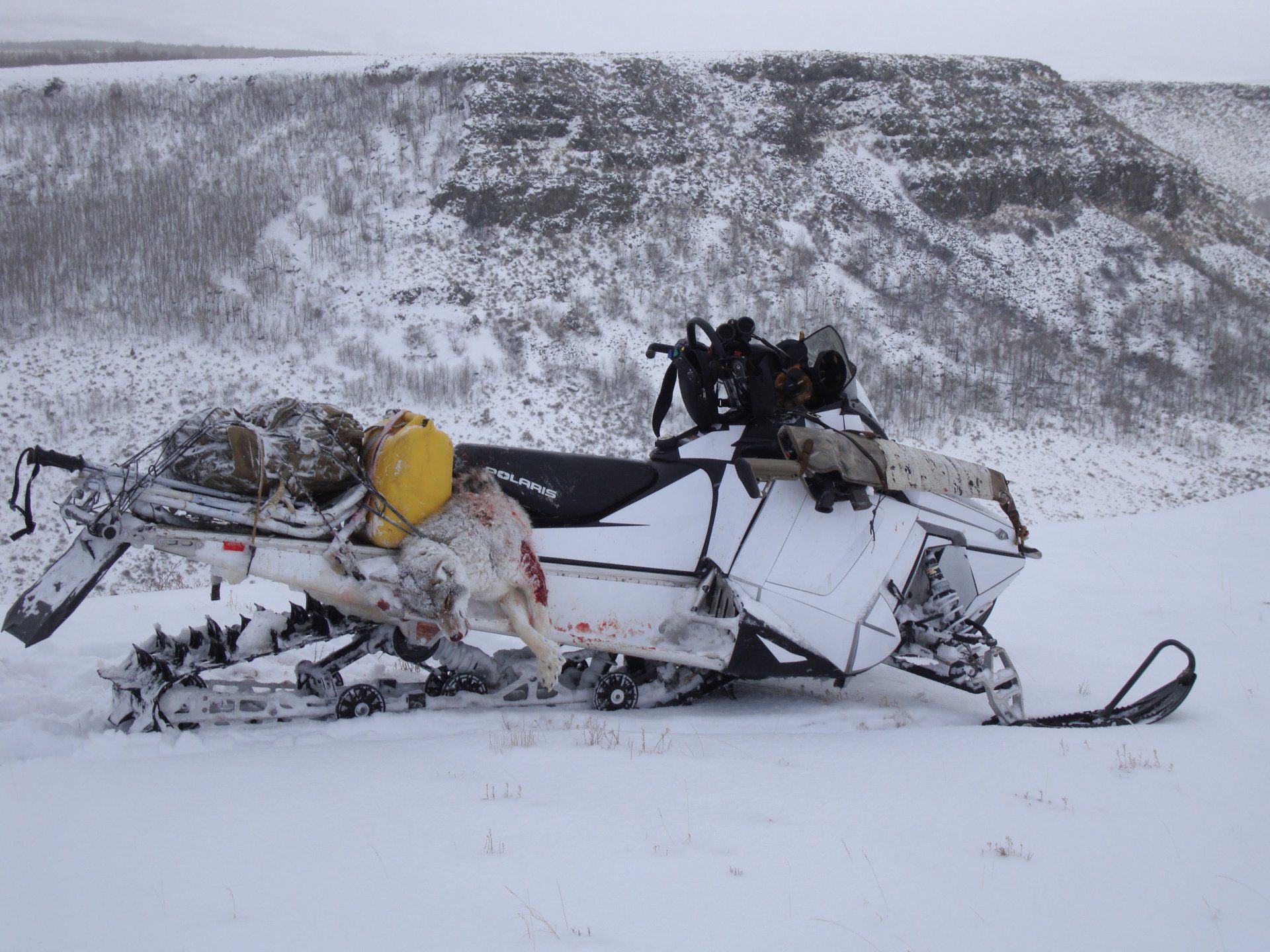 A snowmobile is parked in the snow near a mountain