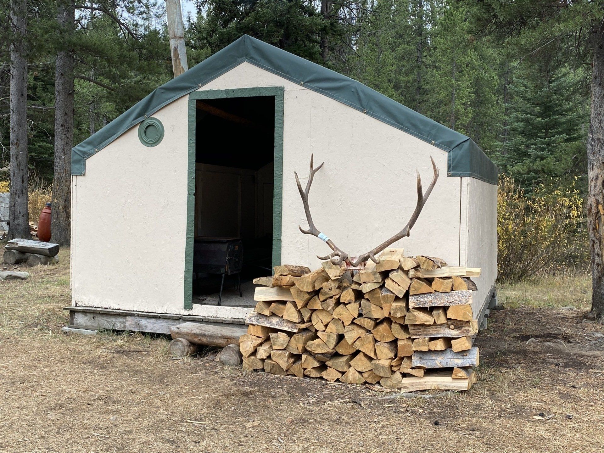 A stack of logs sits in front of a tent