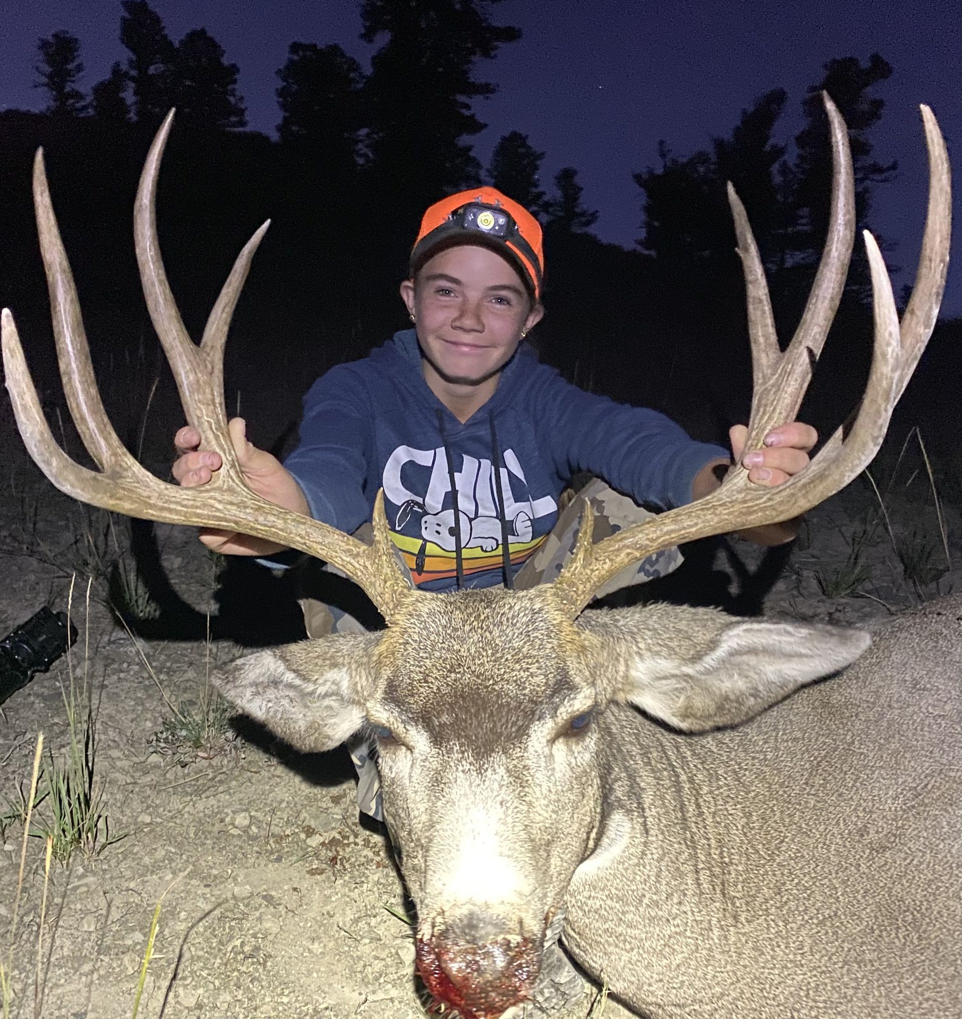 A boy wearing a hoodie that says city holds a deer