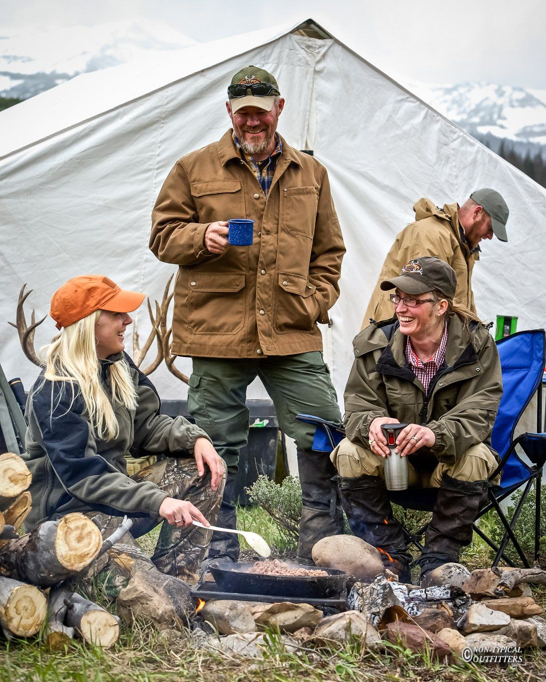 A group of people sitting around a campfire in front of a tent