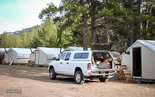 A white truck is parked in front of a row of tents
