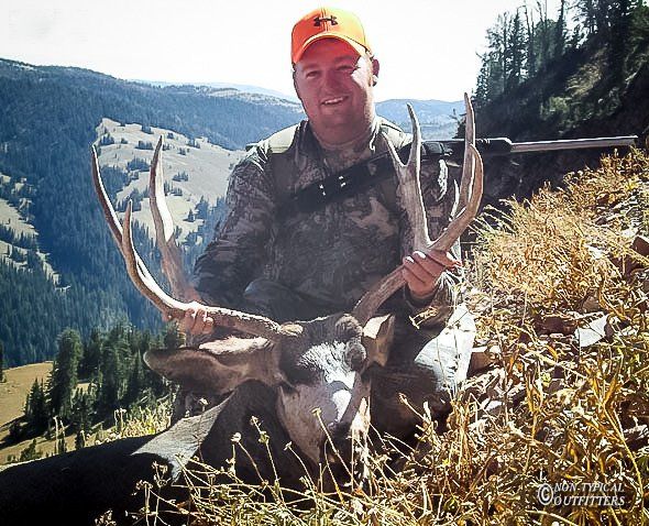 A man in an orange hat is holding a large deer