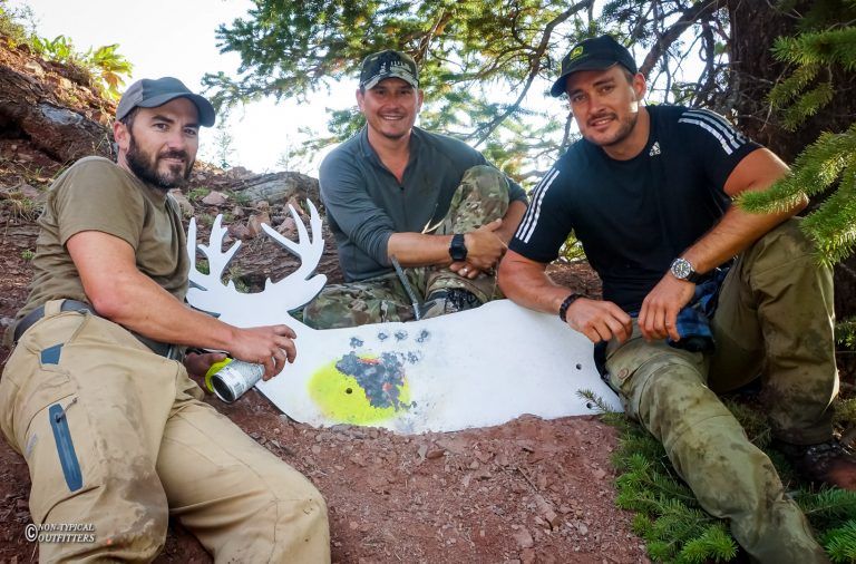 Three men are posing for a picture in front of a deer target