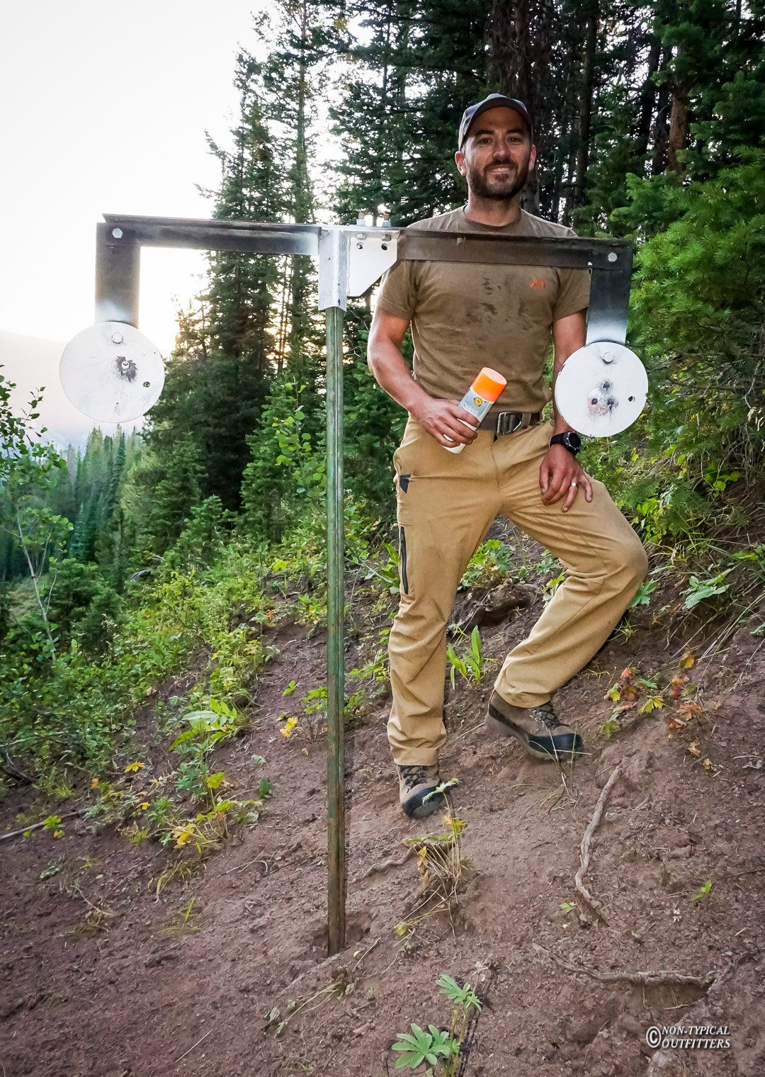 A man is standing next to a target in the woods.