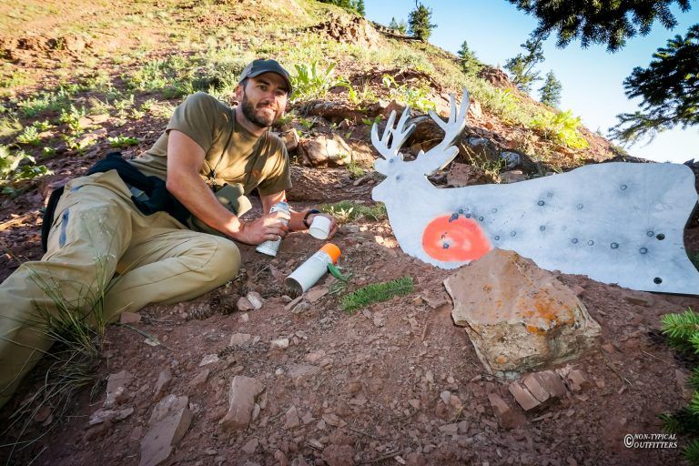 A man is kneeling down in front of a deer target