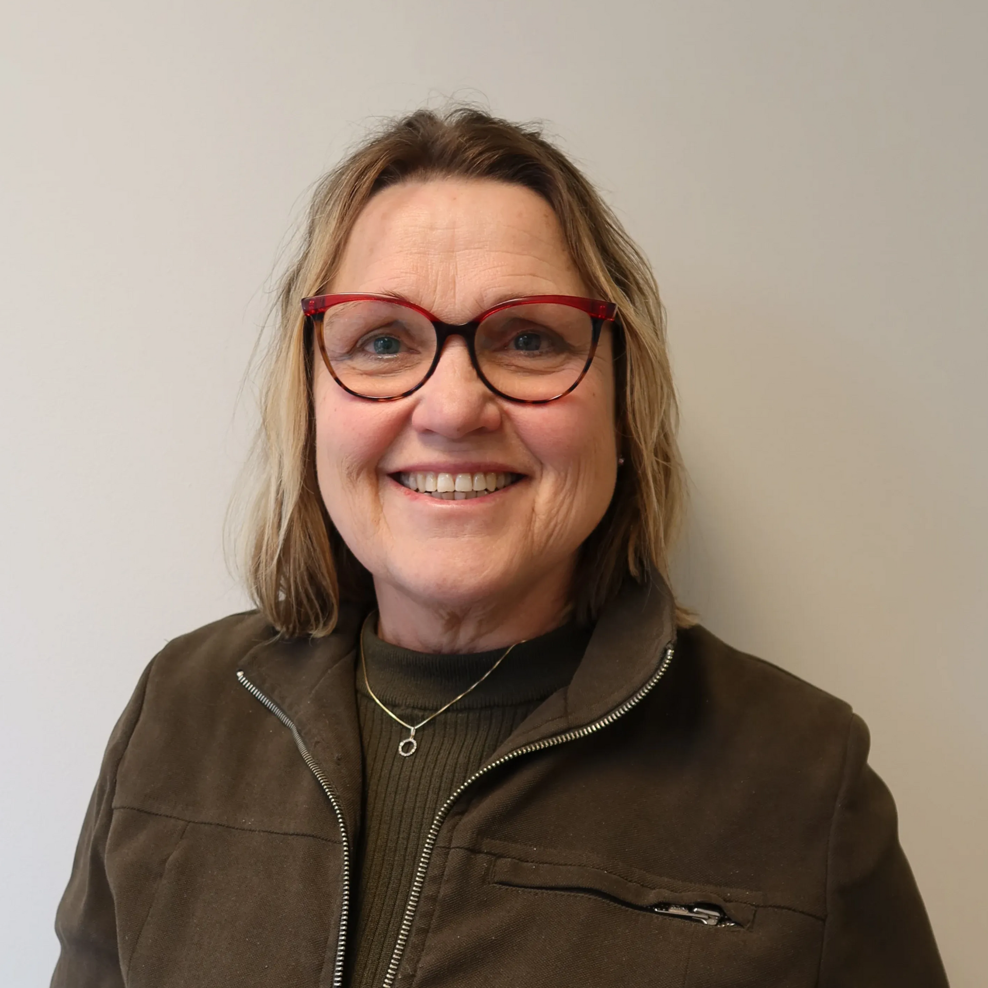 Bendik Grieg Skjold med lys hud og brunt hår iført en hvit polotrendgenser, mot en hvit vegg.