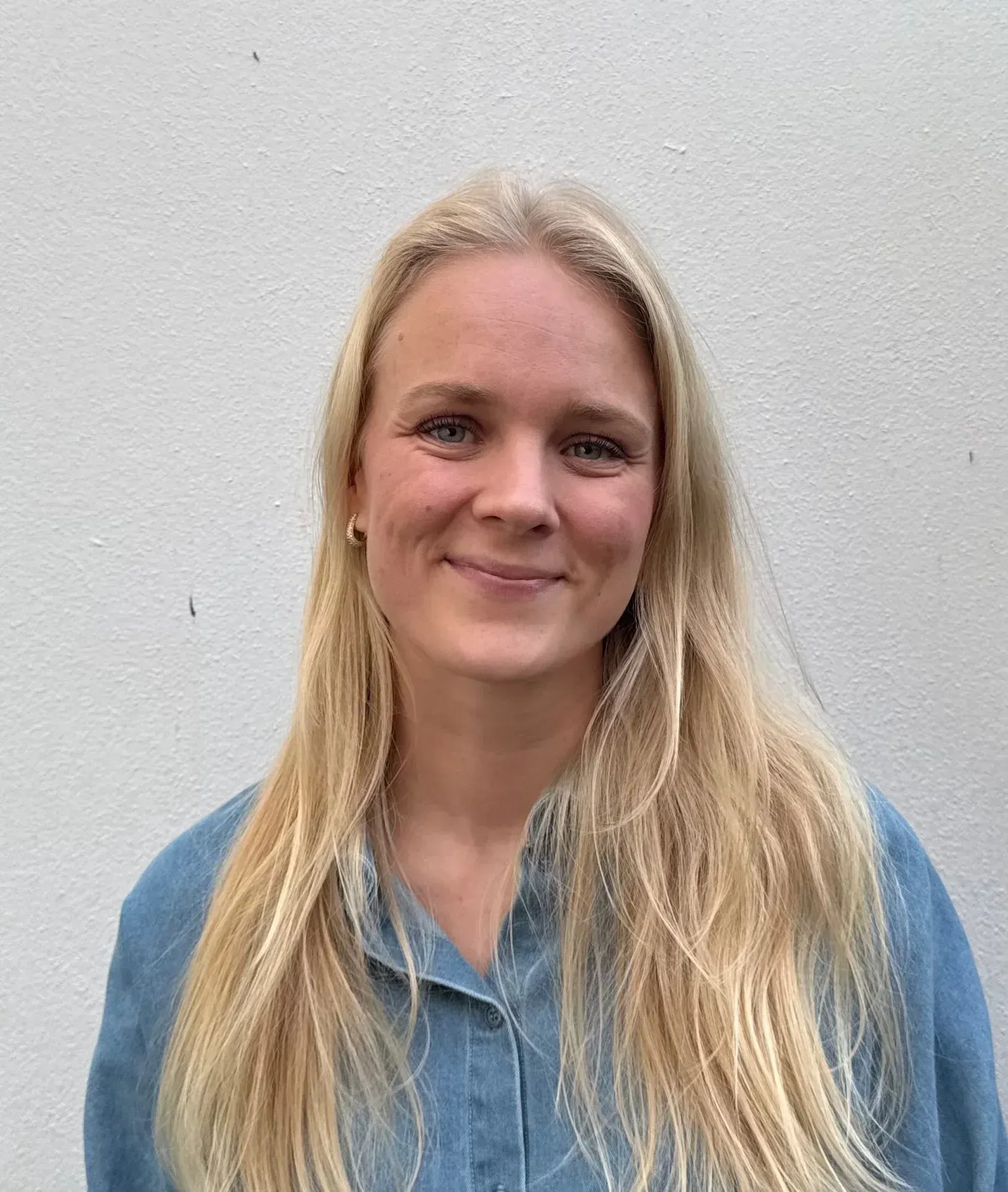 Woman with glasses, smiling, wearing a black top, against a gray background.